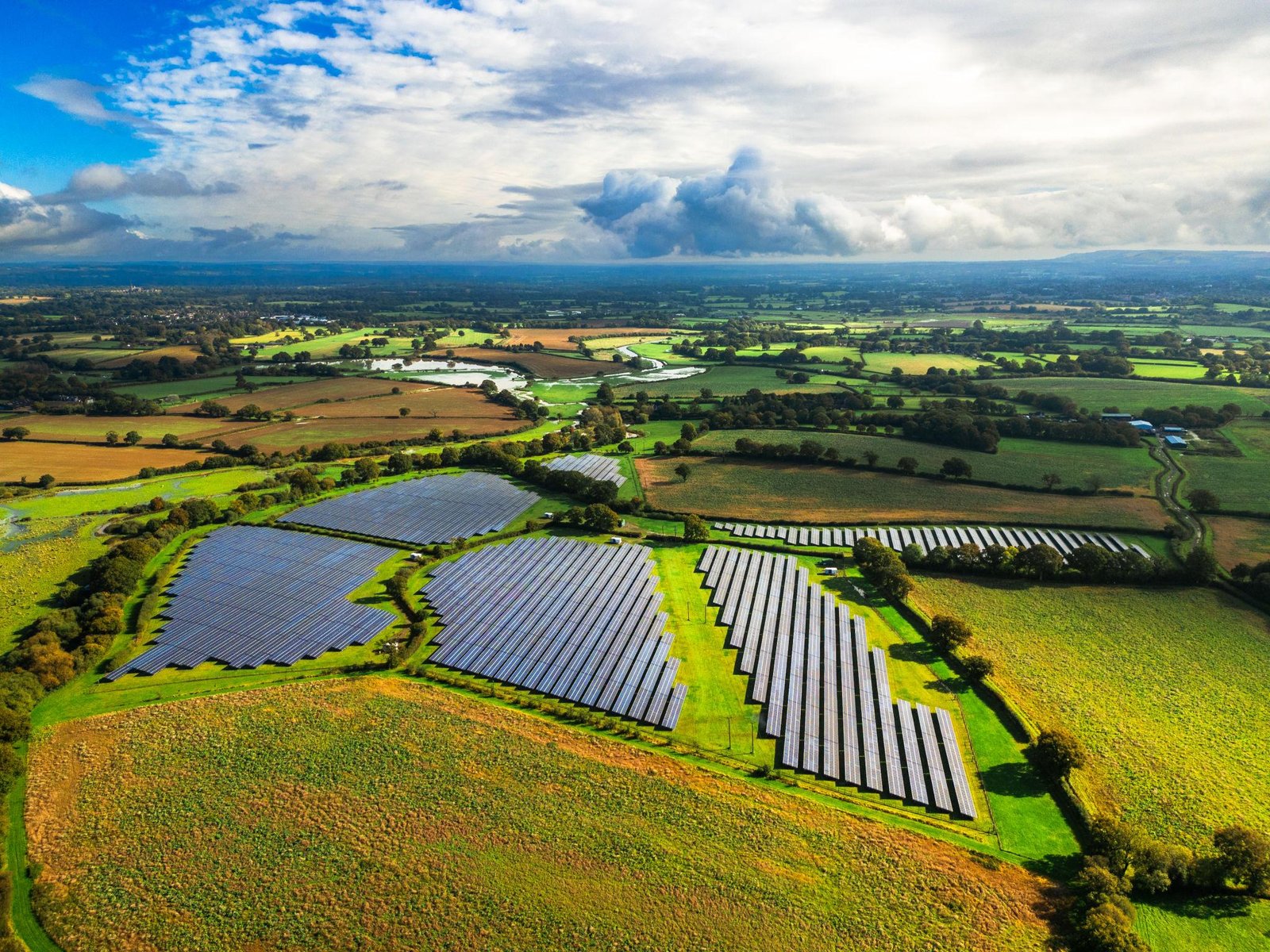 Aerial view of a utility-scale solar farm across green farmland, representing the scale of PV designs delivered by RIH Engineering